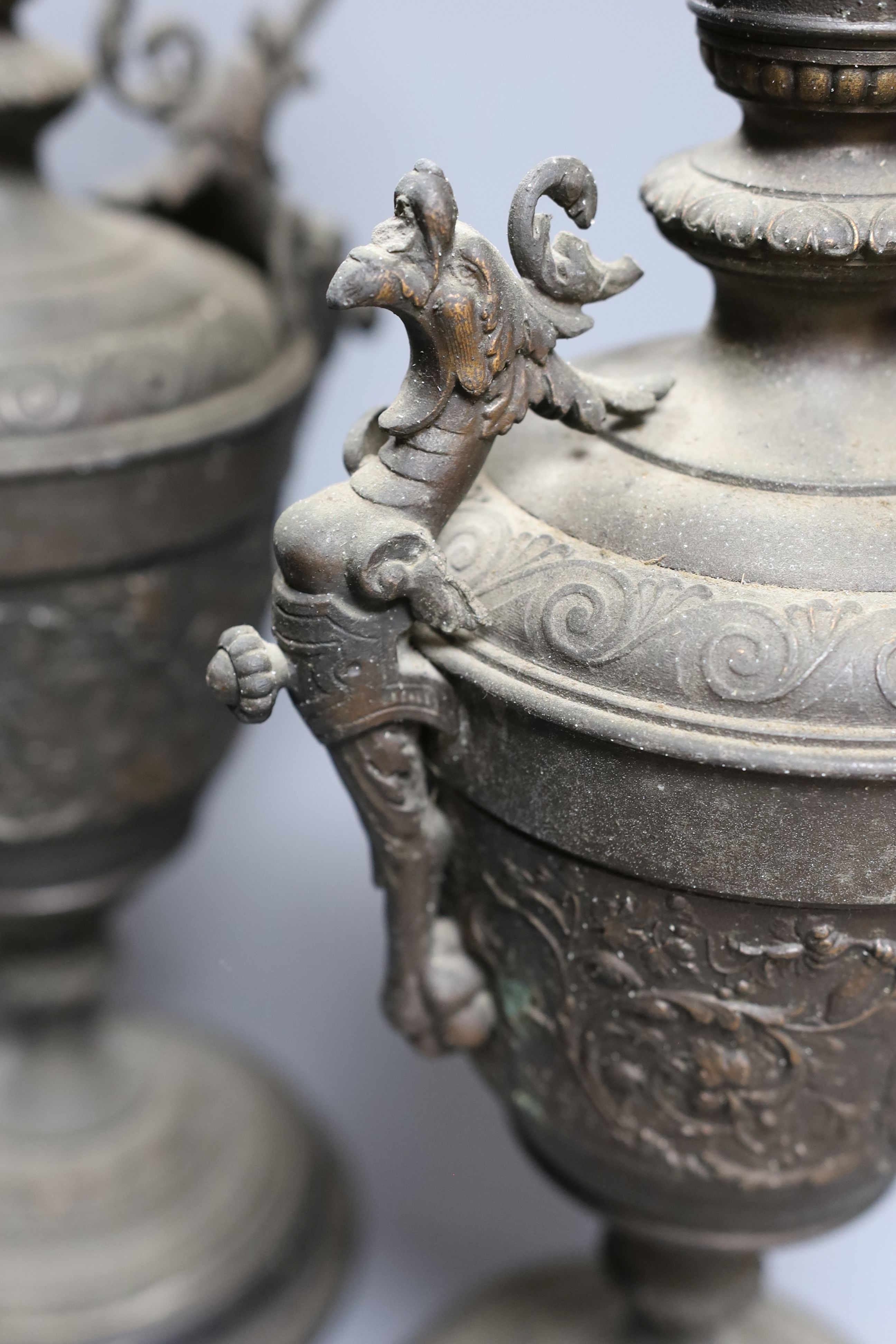 A pair of bronzed metal classical pedestal urns with scroll decoration and satyr masks (one handle detached), height 53cm